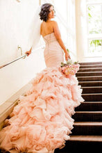 Load image into Gallery viewer, Woman in a pink wedding dress with a ruffled skirt standing on a staircase.
