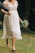Load image into Gallery viewer, Woman in a white dress holding a bouquet in a natural setting