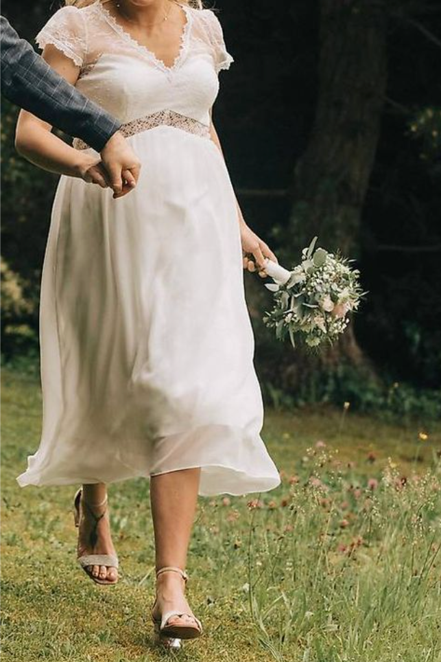 Woman in a white dress holding a bouquet in a natural setting