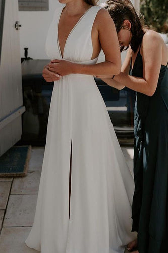 Woman in a white dress standing outdoors with people in the background