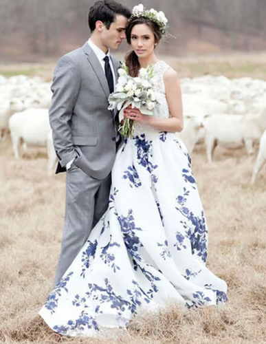 Man and woman in formal attire standing in a field with sheep.