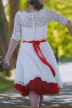 Load image into Gallery viewer, White lace dress with a red belt and skirt worn by a person outdoors.