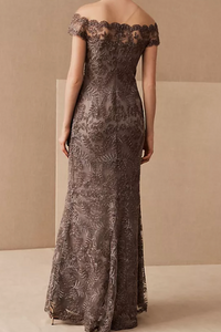 Woman wearing a long, off-shoulder lace dress against a beige background