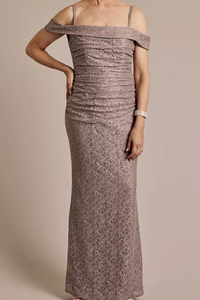 Woman wearing a long, patterned off-shoulder dress against a neutral background