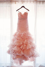 Load image into Gallery viewer, Pink ruffled dress hanging on a hanger against a white curtain.