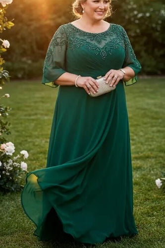 Woman in a green dress standing in a garden with floral decorations at sunset.