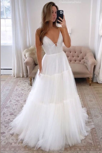 Woman in a white wedding dress taking a mirror selfie in a decorated room.