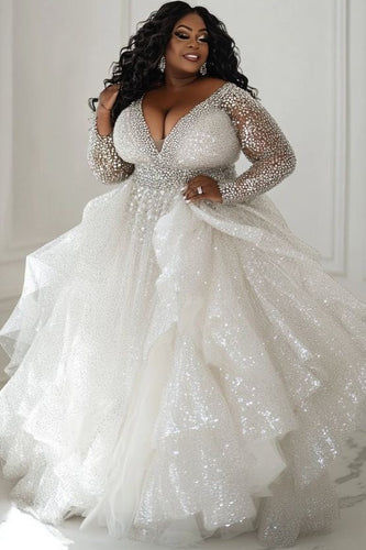 Woman wearing a sparkling white wedding dress in a room with white walls.