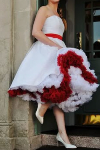 Woman wearing a white strapless dress with a red floral skirt in an urban setting.
