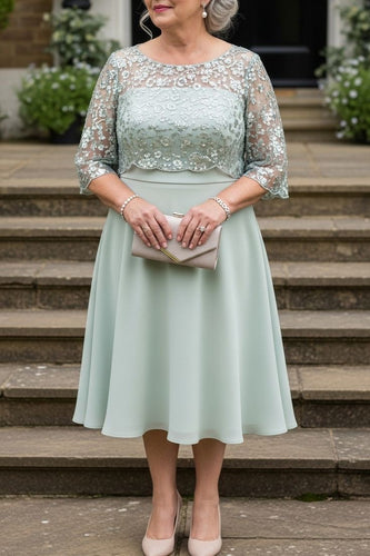 Woman in a light green dress with lace sleeves standing on steps outdoors.