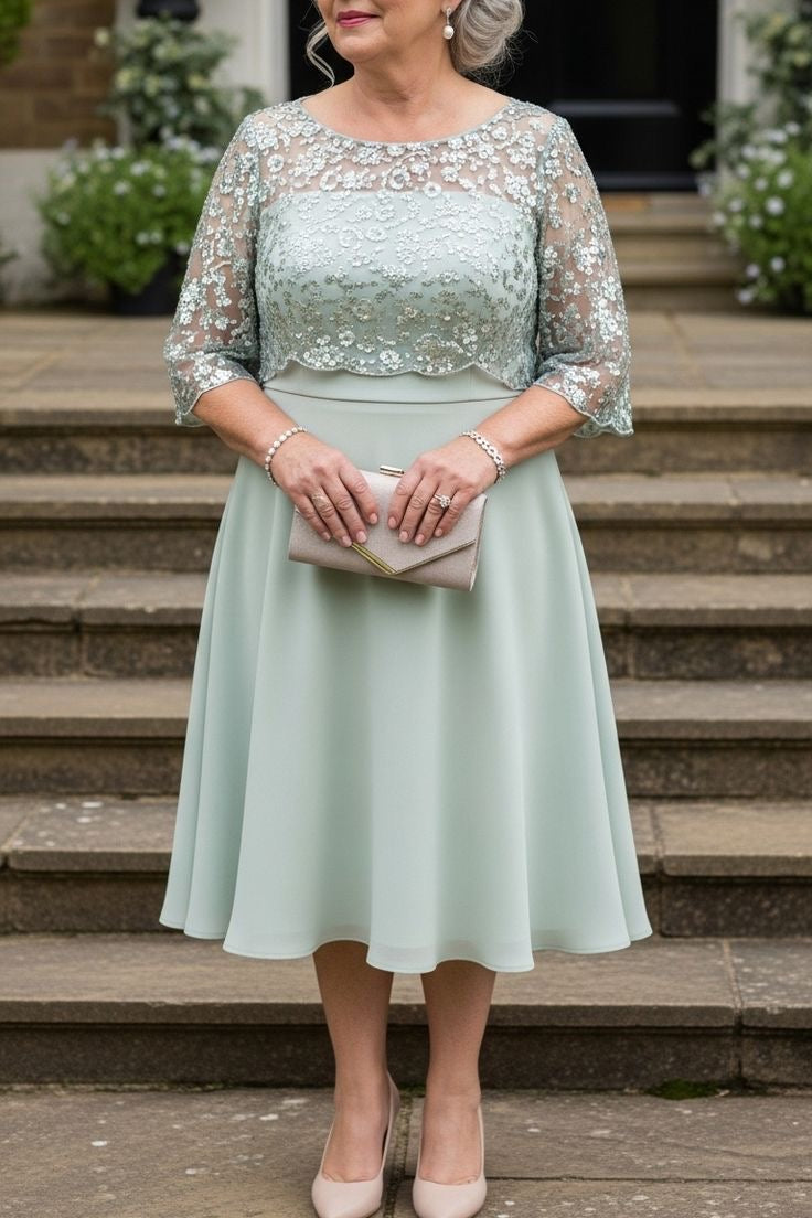 Woman in a light green dress with lace sleeves standing on steps outdoors.