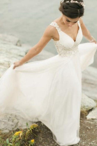 Woman in a white wedding dress standing by a body of water.