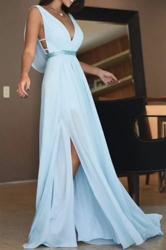 Woman wearing a light blue evening gown with a slit, standing indoors.