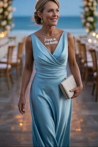 Woman in a light blue dress with 'Forever in our hearts' necklace at an outdoor event.