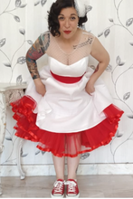 Load image into Gallery viewer, Person wearing a white dress with red accents and red sneakers against a decorative wall.