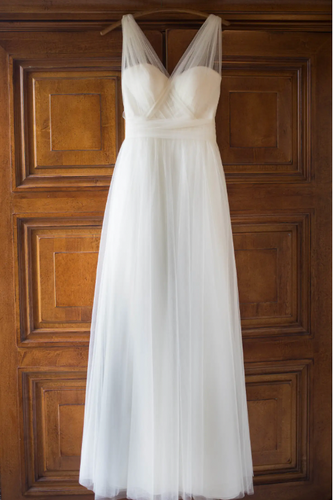 White wedding dress hanging on a wooden door
