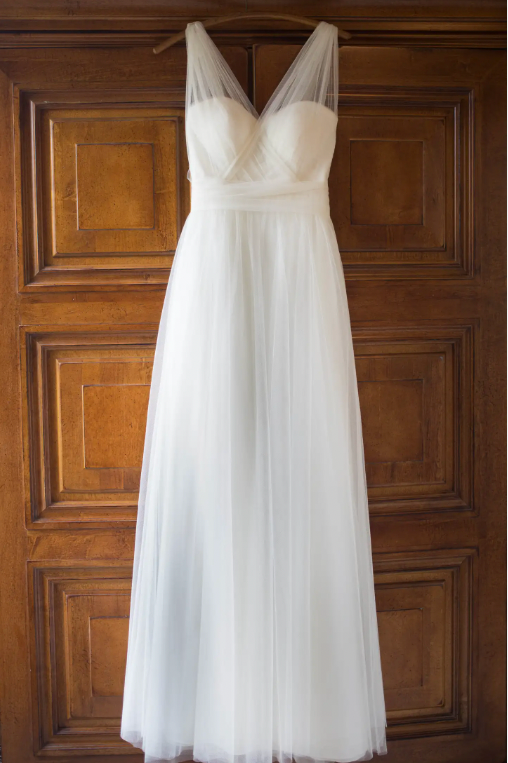 White wedding dress hanging on a wooden door
